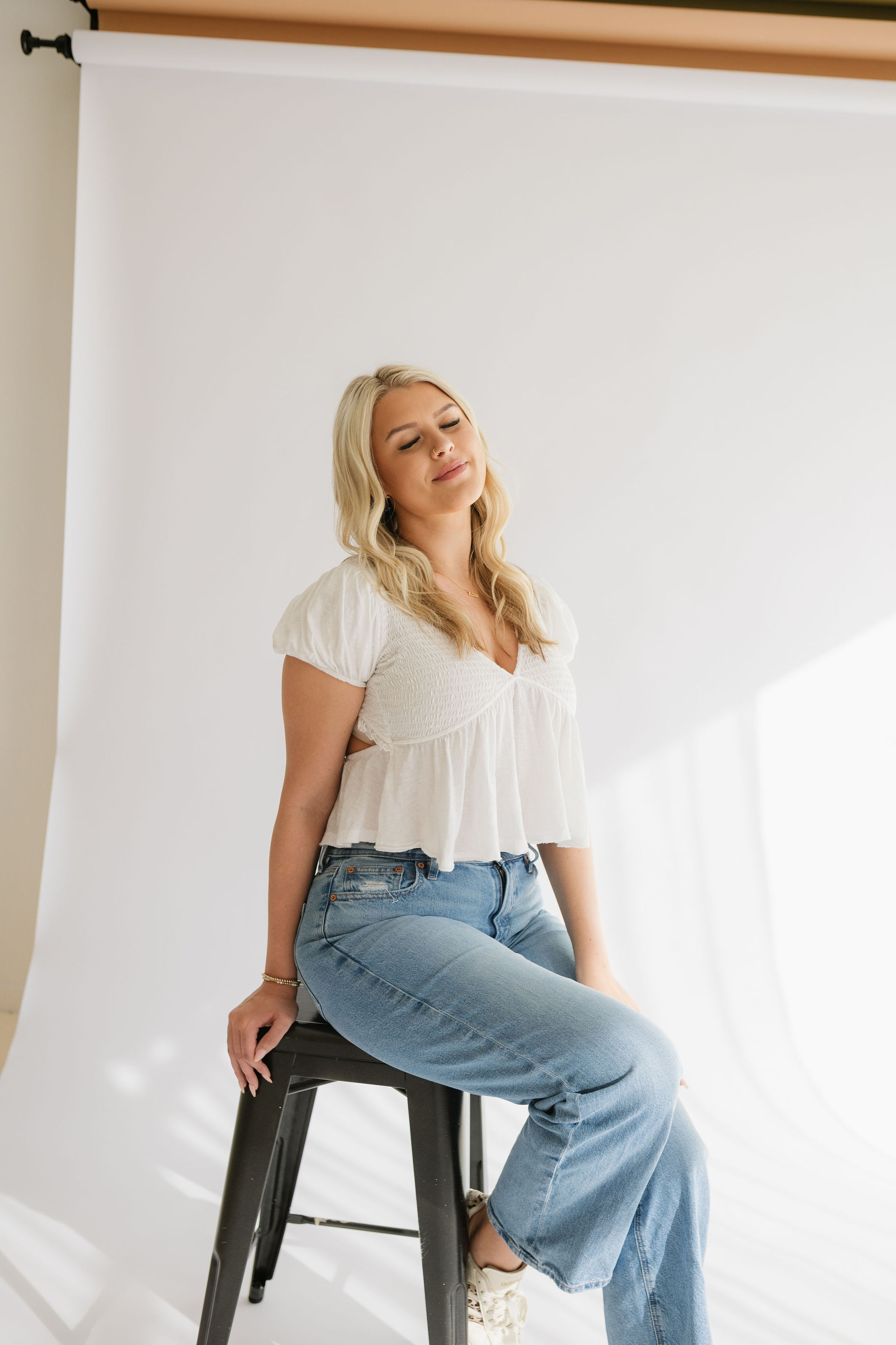 Averie in a neutral studio portrait wearing a white blouse and jeans