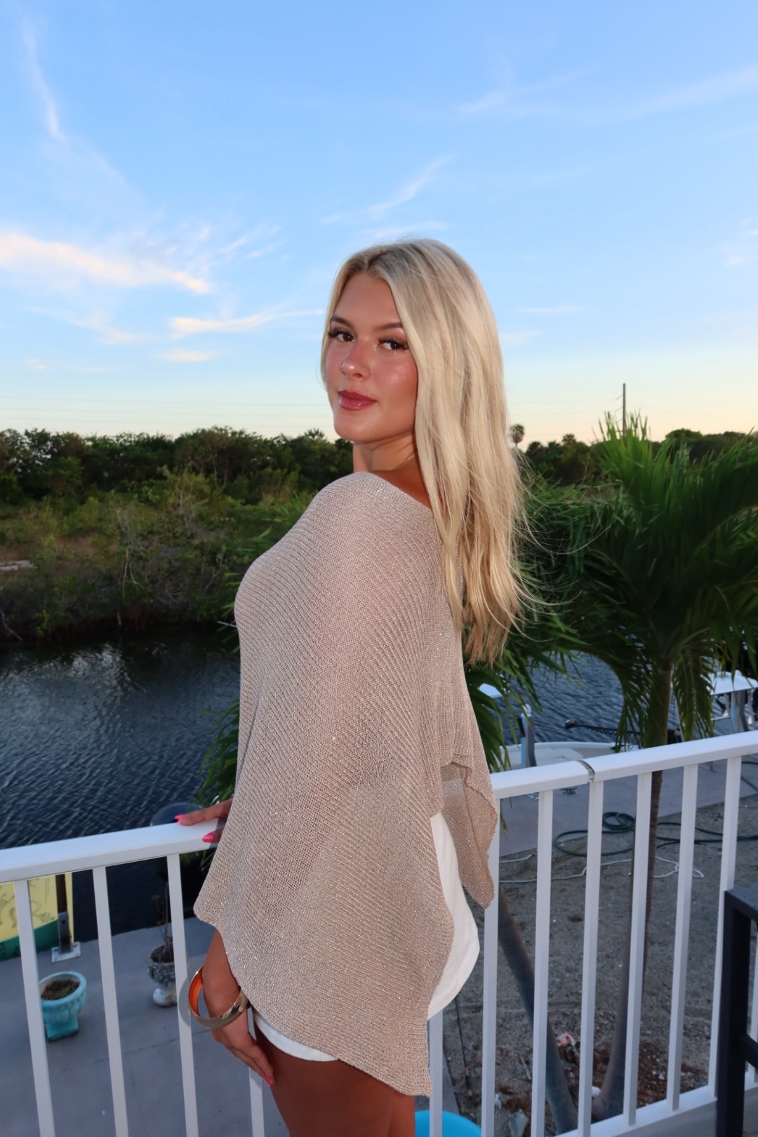 Averie in a taupe wrap on a balcony at sunset