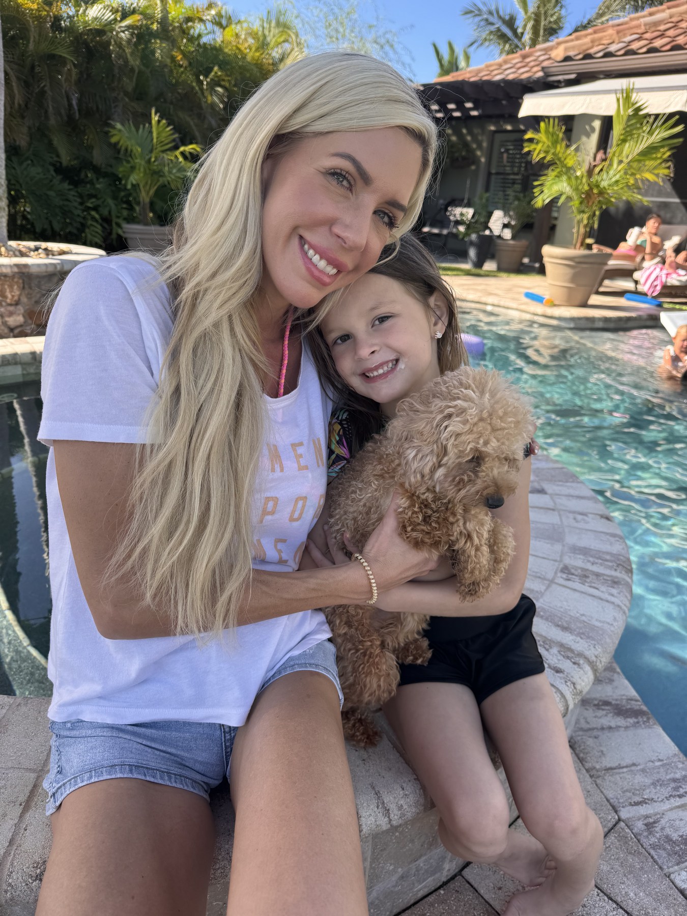 Poolside lifestyle portrait with a child and a small dog